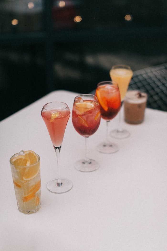 Assortment of brightly colored cocktails with citrus garnishes on an outdoor table.